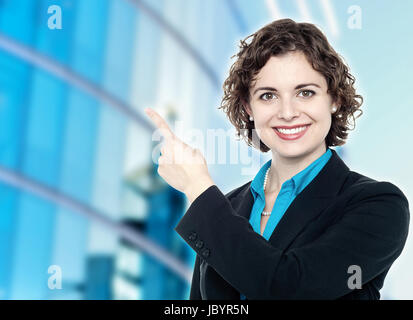 Business lady pointing at something, outdoors. Stock Photo