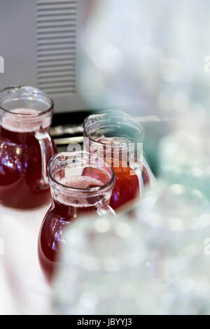 upside-down glasses on counter with gugs of red drink Stock Photo