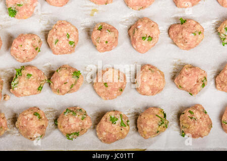 Freshly formed raw meatballs with herbs on oven pan ready to bake Stock Photo