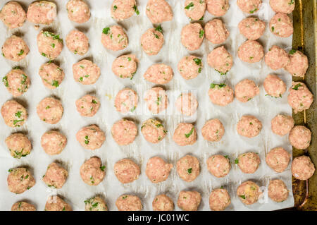 Freshly formed raw meatballs with herbs on oven pan ready to bake Stock Photo