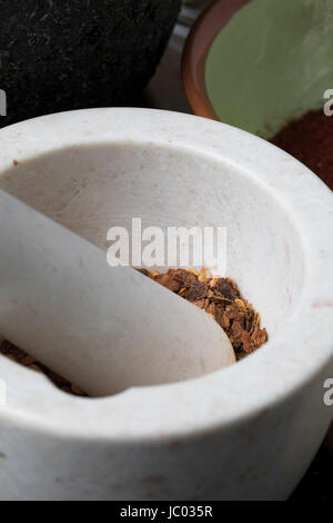 Vertical orientation close up of porcelain mortar and pestle with crushed dried chili pepper. Stock Photo