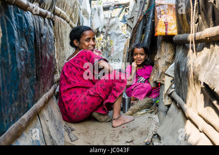 A woman and her child are sitting between slum dwellings in Topsia slum Stock Photo