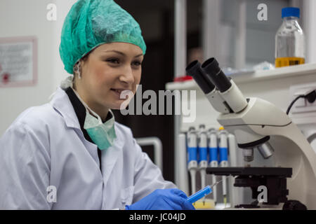 Beautiful female medical or scientific researcher or woman doctor hold pipette in a laboratory. Young scientist doing some research. Stock Photo