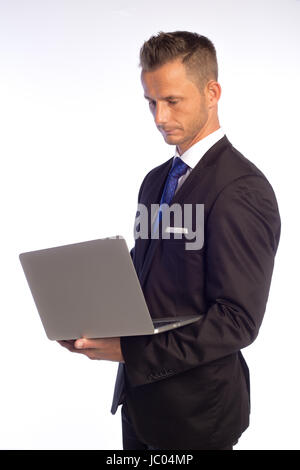 Young standing man in business suit holding laptop Stock Photo