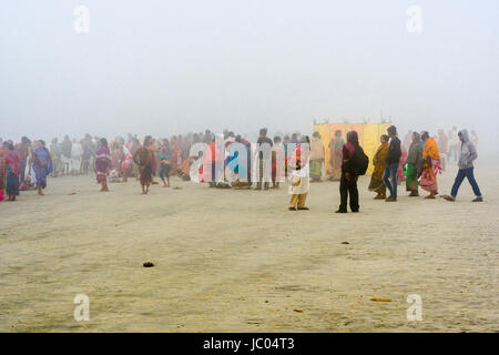 Hundreds of pilgrims are gathering on the beach of Ganga Sagar in the morning fog, celebrating Maghi Purnima festival Stock Photo