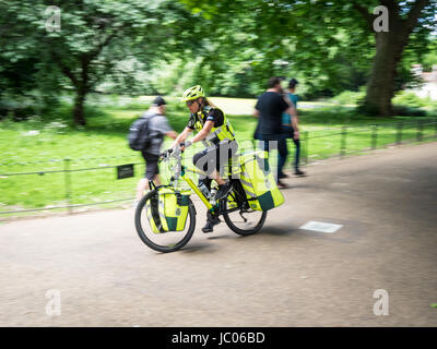 A London Ambulance Service Bike Paramedic rushes through St James Park to a call with blue lights flashing. Bike Paramedic in Motion. Stock Photo