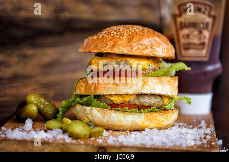 Homemade Maxi Burger with grilled beef steak, lettuce, cheese, tomato, onion, barbecue sauce, honey mustard pickles Stock Photo