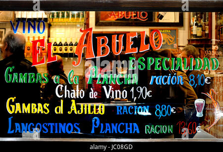 Madrid, Spain. La Casa del Abuelo restaurant - menu detail painted on window, customers inside Stock Photo