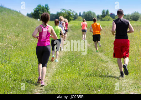 Outdoor cross-country running, group of young active people running in nature Stock Photo