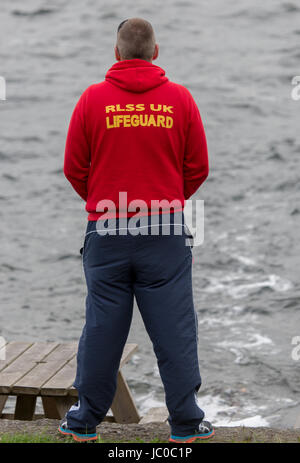 A Royal Life Saving Society Lifeguard looks out across a lake Stock Photo