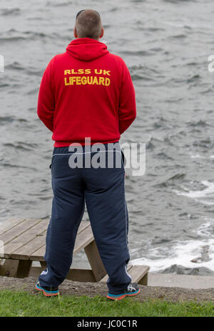 A Royal Life Saving Society Lifeguard looks out across a lake Stock Photo