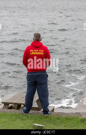 A Royal Life Saving Society Lifeguard looks out across a lake Stock Photo