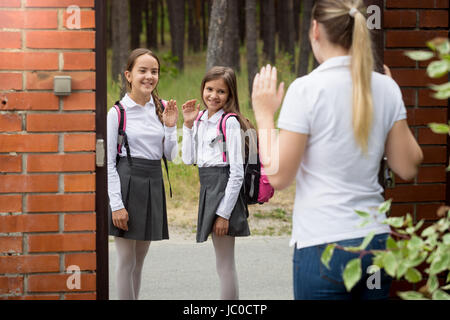 Young mother seeing her two daughters off to school Stock Photo