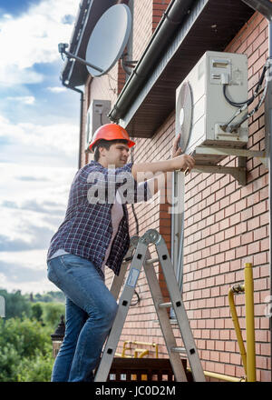 Portrait of young technician repairing outside air conditioning unit Stock Photo