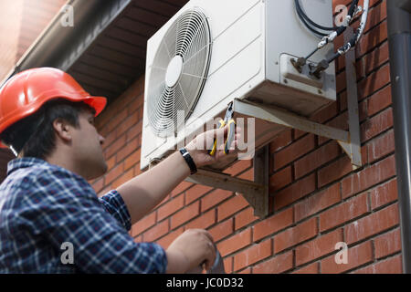 Portrait of technician in hardhat connecting outdoor air conditioning unit Stock Photo