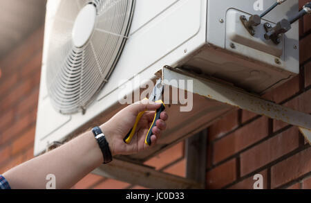 Closeup photo of male technician installing outdoor air conditioning unit Stock Photo