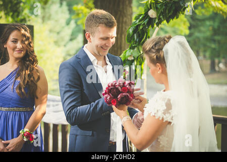 Toned portrait of happy newly married couple putting wedding rings Stock Photo