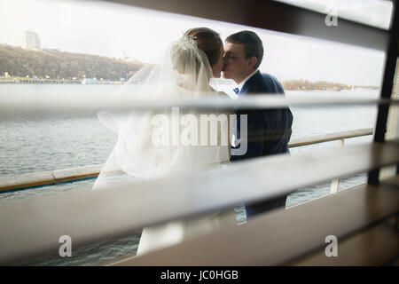Portrait through window jalousie of kissing happy newly married couple Stock Photo