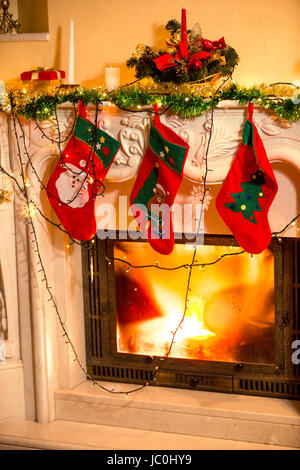 Closeup interior photo of three Christmas stockings hanging on decorated fireplace Stock Photo