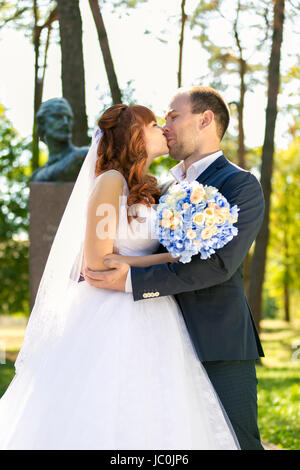 Closeup portrait of just married couple kissing in park at sunny day Stock Photo