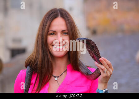 Young woman holding Indian cobra in the street of Jaipur, India. Jaipur is the capital and largest city of the Indian state of Rajasthan. Stock Photo