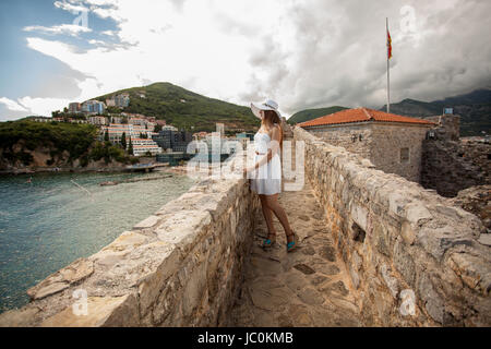 Beautiful young woman walking on top of stone wall at old castle Stock Photo