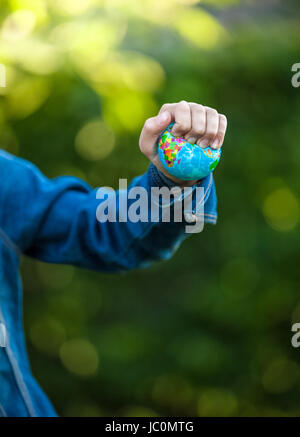 Closeup shot of little girl squeezing Earth globe at hand Stock Photo