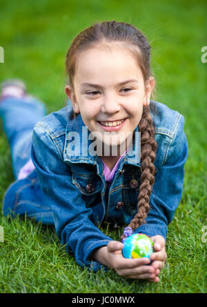 Little girl holding globe in hands and lying at park Stock Photo