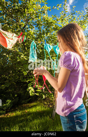 Outdoor photo of young girl drying clothes on clothesline Stock Photo