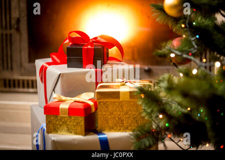 Stack of packed gift boxes under Christmas tree at fireplace Stock Photo