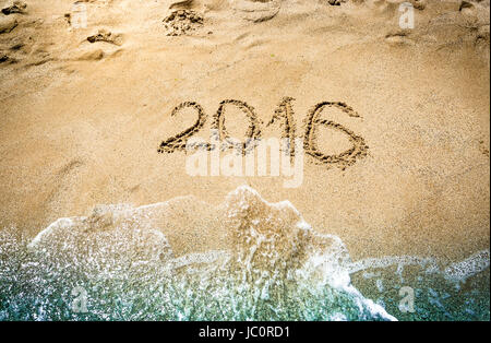 Closeup shot of 2016 digits written on wet sand at seashore Stock Photo
