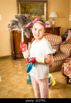 Portrait of smiling girl doing cleaning posing with feather brush Stock Photo