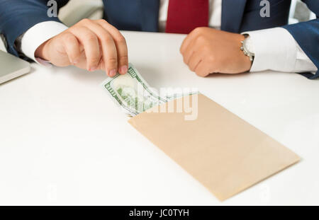 Closeup photo of businessman pulling banknote out of envelope lying on table Stock Photo
