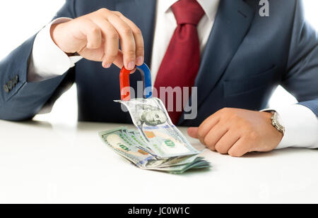 Conceptual photo of businessman pulling money from stack on table with the magnet Stock Photo