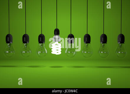 Conceptual image of glowing energy saving bulb and old dark bulbs on wires over green background Stock Photo