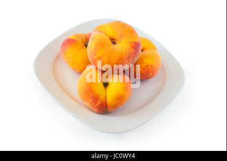 New variety of flat peaches lies on a white plate against a white background Stock Photo