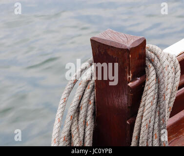 Coiled rope hung on wooden post on boat. Stock Photo