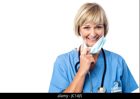 Experienced lady doctor removing her surgical mask Stock Photo