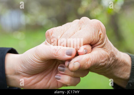 Close up picture of a young woman's hands holding an elderly female's hands Stock Photo