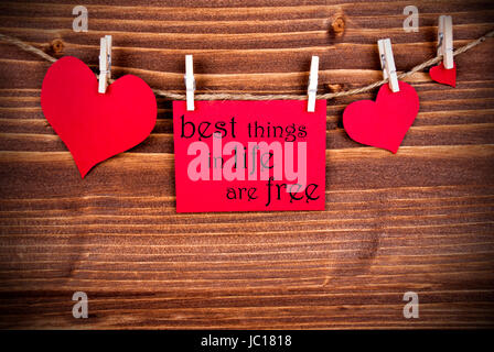 The Saying Best Things in Life are Free on a red Label with Hearts on a Line Hanging on Wooden Background Stock Photo