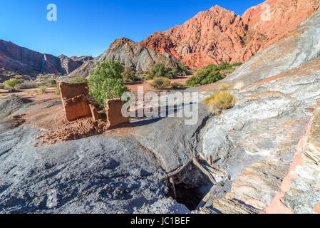 Ruined adobe building next an abandoned copper mineshaft with red hills in the background of the town Titihoyo near Tupiza, Bolivia Stock Photo