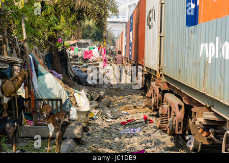 The dwellings in Park Circus slum area are located right next to the railroad tracks, a train is passing through Stock Photo