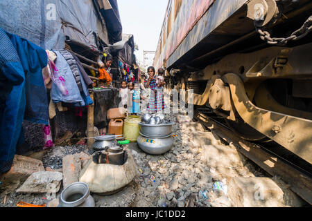 The dwellings in Park Circus slum area are located right next to the railroad tracks, a train is passing through Stock Photo