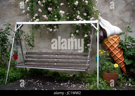 A giant plastic ice cream cone can be seen next ot a Hollywood swing in a garden in Dresden, Germany, 13 June 2017. Photo: Arno Burgi/dpa-Zentralbild/dpa Stock Photo