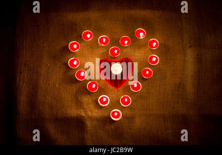 Decorative red candles forming heart shape on linen cloth Stock Photo