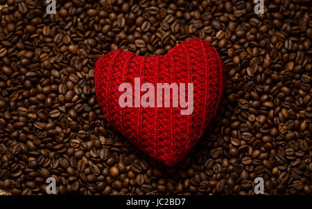 Macro photo of red knitted heart lying on coffee beans Stock Photo