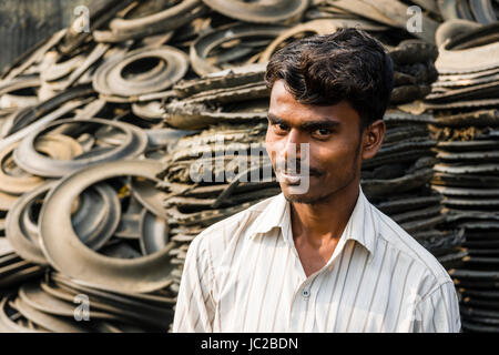 Portrait of a man cutting recyclable rubber materials from truck tyres in Dhapa Garbage Dump