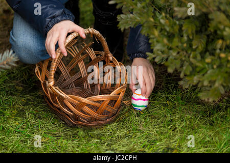 Closeup photo of little girl putting colorful Easter egg in the basket Stock Photo