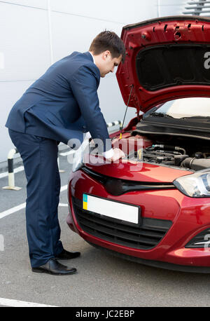 Adult man in suit looking under car bonnet Stock Photo