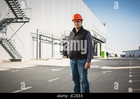 Portrait of young engineer in hard hat posing at warehouse Stock Photo